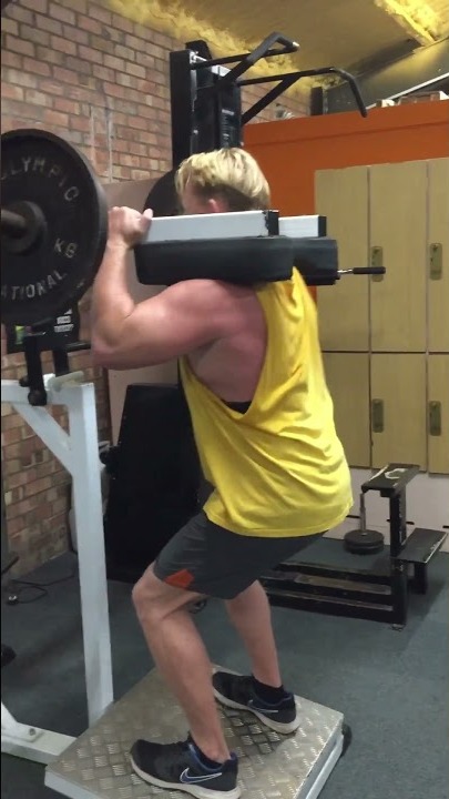 Utley, personal trainer, performing a loaded standing calf raise in the gym